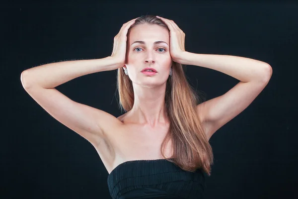 Mulher bonita segurando a cabeça em mãos de pé contra backgr preto — Fotografia de Stock