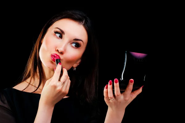 Mujer joven aplicando lápiz labial mirando al espejo —  Fotos de Stock