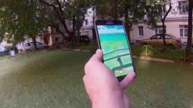 Bir adam tarafından Bahçe üzerinde yürürken cep telefonundan oynanan Pokemon gitmek app