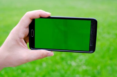 Akıllı telefon yeşil bahar arka planı elinde tutan adam