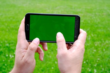 Akıllı telefon yeşil bahar arka planı elinde tutan adam