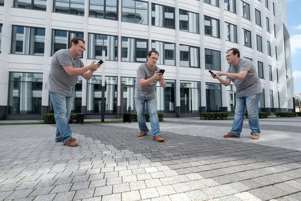 Drie mannen met een mobiele telefoon voor een witte business centrum — Stockfoto