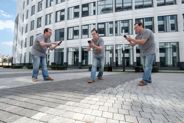 Drie mannen met een mobiele telefoon voor een witte business centrum — Stockfoto