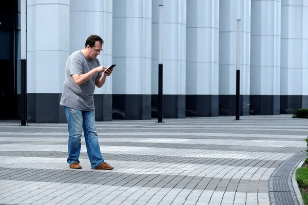 흰색 비즈니스 센터 앞에서 휴대 전화를 가진 남자 보고 — 스톡 사진