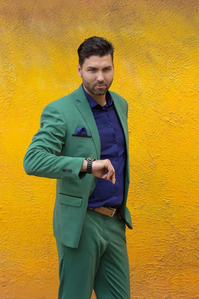 Mann im grünen Anzug auf gelbem Wandhintergrund. — Stockfoto