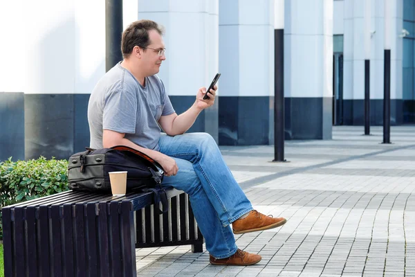 Bello uomo adulto in abbigliamento casual utilizzando il caffè del telefono cellulare in f — Foto Stock