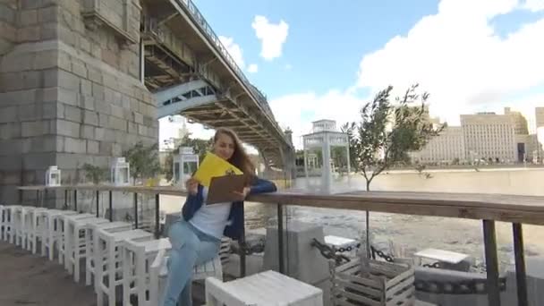 Joven mujer feliz menú de lectura en la calle café el día de otoño — Vídeos de Stock