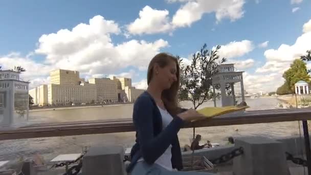 Joven mujer feliz menú de lectura en la calle café el día de otoño — Vídeos de Stock