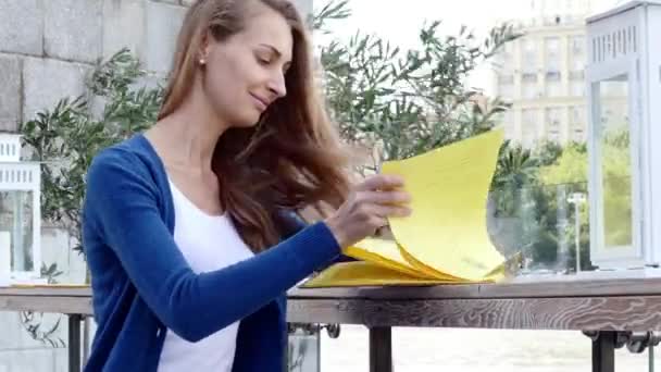 Jovem mulher feliz lendo menu no café de rua dia de outono — Vídeo de Stock