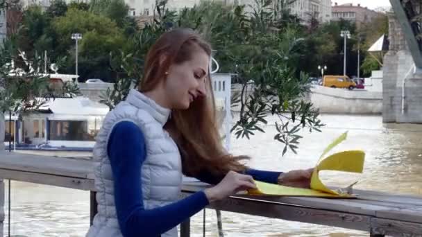 Joven mujer feliz menú de lectura en la calle café el día de otoño — Vídeo de stock