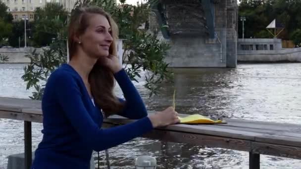 Молодая счастливая женщина читает меню в уличном кафе осенний день — стоковое видео