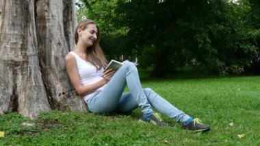 Sarışın kız bir parkta bir kitap okuma