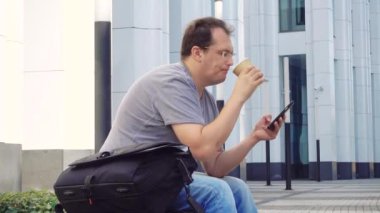 Şehir stili. Cep telefonu kahve beyaz işletme binası önünde kullanarak rahat kıyafet yakışıklı yetişkin adam.
