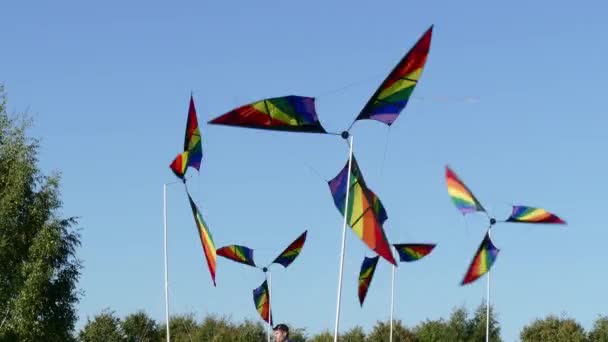 Větrný mlýn větrník s 3 různě barevných Lopatky otáčí na tyči na pozadí modré oblohy. — Stock video