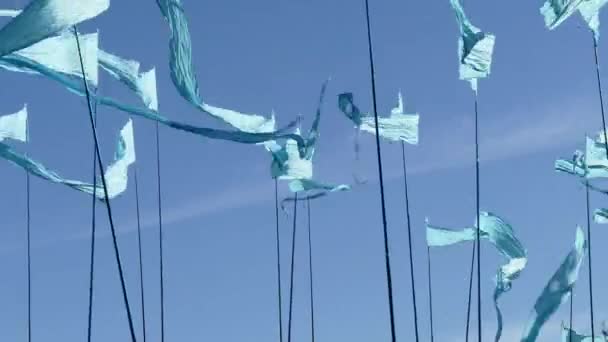 Panorering skott mot en klarblå himmel bakgrund av färgglada sträng vimpel triangel flaggor används för festligheter eller grand öppningar blåser i vinden. — Stockvideo