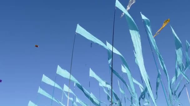 Schwenkschuss vor einem klaren blauen Himmel Hintergrund aus bunten String-Wimpel-Dreieck-Fahnen, die für Feiern oder große Eröffnungen im Wind verwendet werden. — Stockvideo