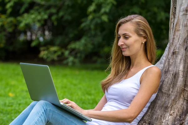 Young woman sitting on the grass with laptop. — Stock Photo, Image