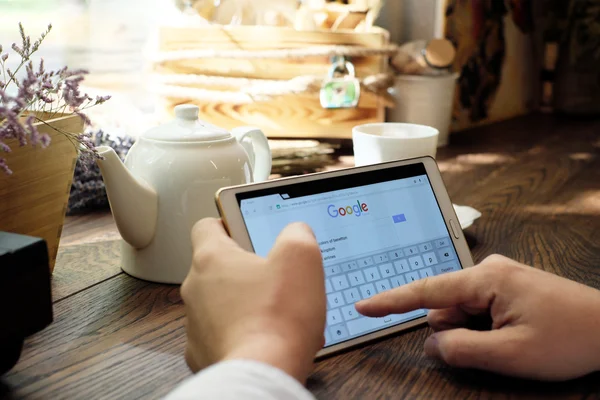 Hombre sosteniendo una tableta blanca y escribiendo para buscar en Google — Foto de Stock