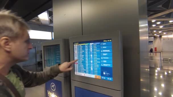 Homme adulte utilisant des informations sur l'écran tactile dans l'aéroport international de Vnukovo — Video