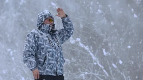 De mens staat alleen tegen witte sneeuwstorm en sneeuwstorm, een sneeuwval. — Stockvideo