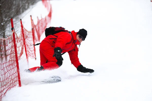 Snowboard binicisi hızlı bir şekilde karlı dağ yamacına doğru gidiyor. Palyaço kışı günü beyaz kar yağıyor.. — Stok fotoğraf