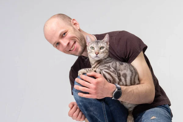 Un homme positif tenant un gros chat bengale — Photo