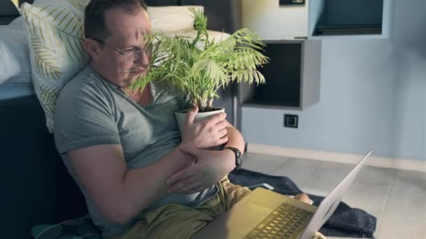 Mann sieht Horrorfilm, wie er sich mit einer Hausblume umarmt — Stockvideo