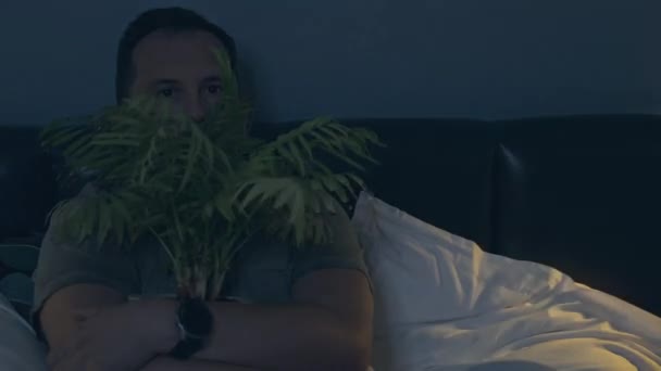 Man kijken naar een horror film knuffelen met een home bloem — Stockvideo