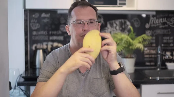 Man sniffs mango — Stock Photo, Image