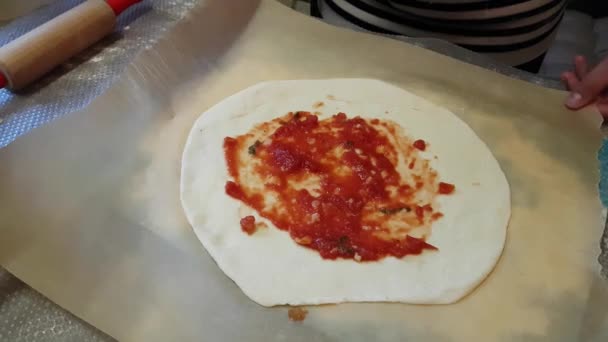 Ребенок кладет томатную пасту на пиццу — стоковое видео