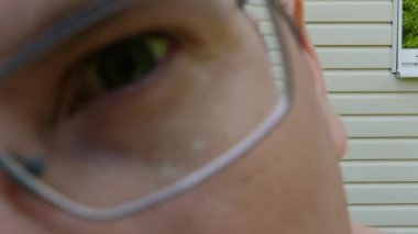 Gözlüklü adam kameraya bakıyor.