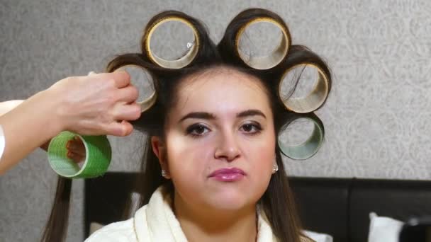 Friseurin zieht Lockenwickler an Frau mit langen Haaren an — Stockvideo