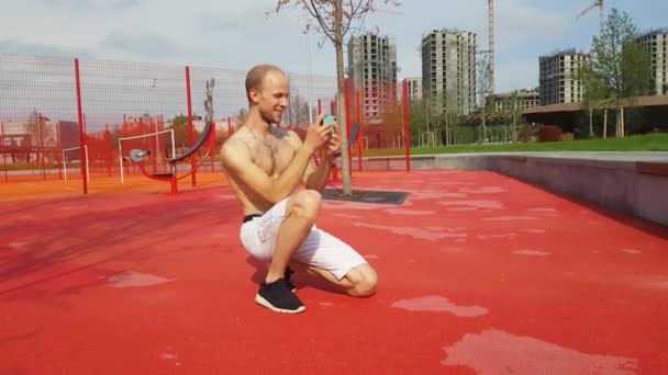 Manden bruger en smartphone som kamera på legepladsen – Stock-video