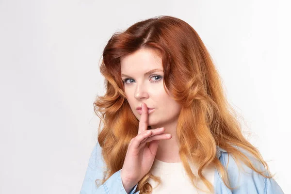 Retrato de jovem mulher de negócios mantendo o dedo em seus lábios e pedindo para manter o silêncio, isolado sobre fundo branco — Fotografia de Stock