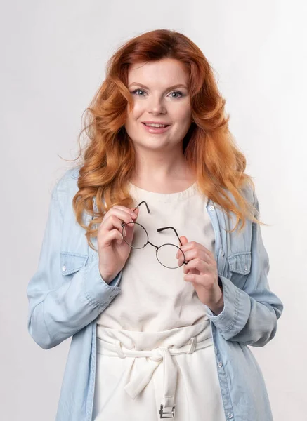 Fashionable glasses for vision correction in the hands of a beautiful redhead woman — Stock Photo, Image