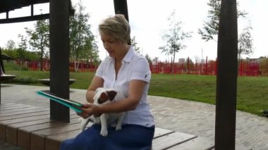 Kadın tabletle küçük bir köpekle yürüyor.