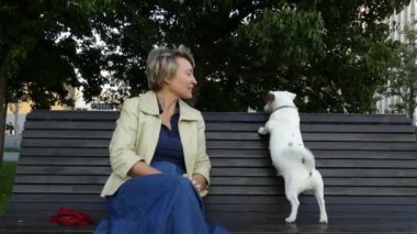 Hamile bir köpekle parkta oturan kadın.
