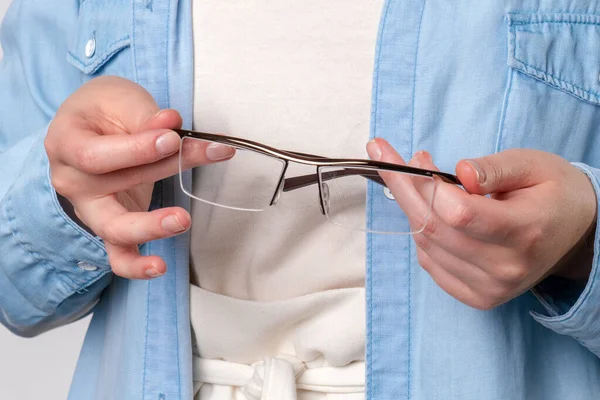 Mujer jengibre sostiene las gafas en las manos — Foto de Stock