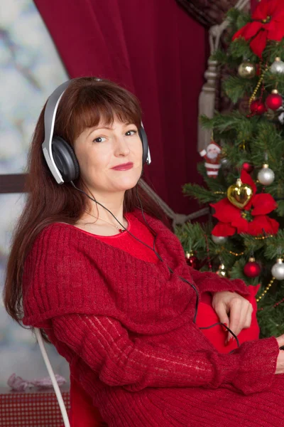 Belle femme adulte écoutant de la musique contre l'arbre de Noël — Photo