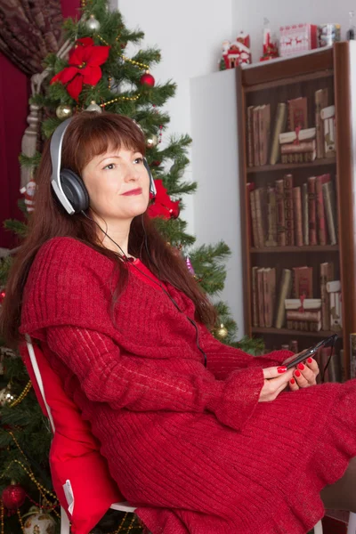 Poslech hudby pro dospělé ženy proti vánoční strom — Stock fotografie