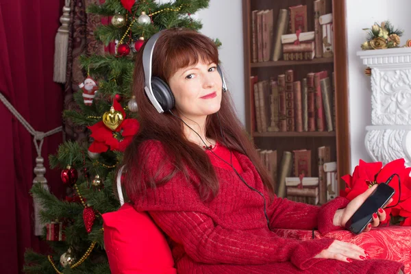 Femme adulte écoutant de la musique contre l'arbre de Noël — Photo