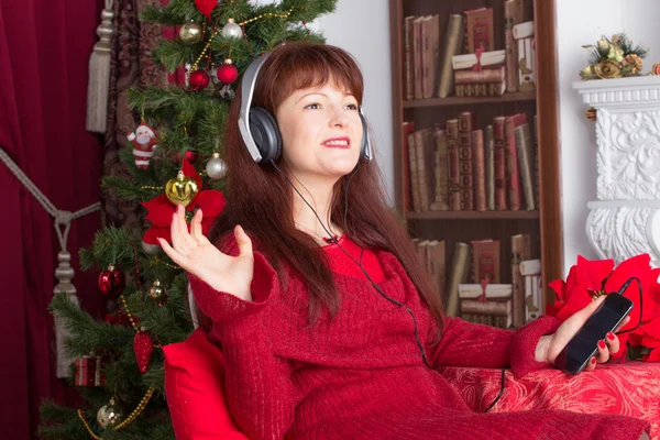 Femme adulte écoutant de la musique contre l'arbre de Noël — Photo