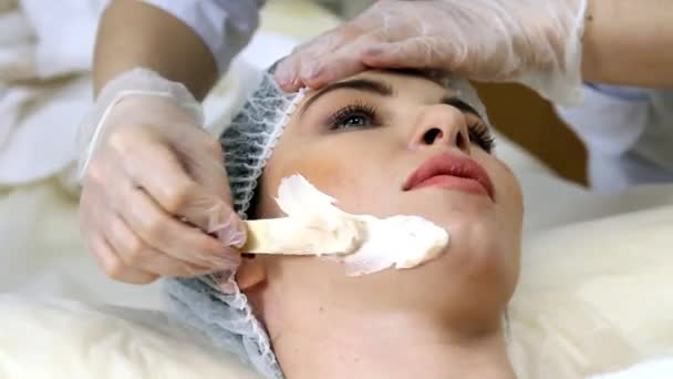Aplicando máscara facial no rosto da mulher no salão de beleza — Vídeo de Stock