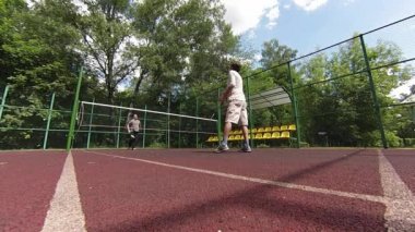 iki adam sahada badminton oynarken