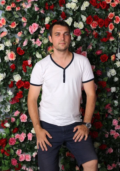 Man on the flowers wall background. — Stock Photo, Image