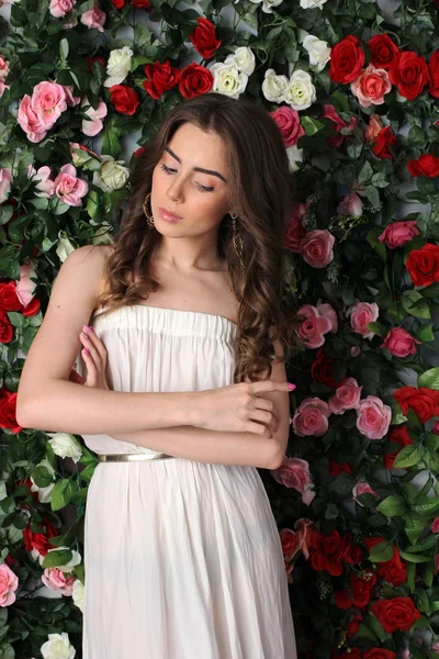 Menina de vestido branco posando no fundo floral — Fotografia de Stock