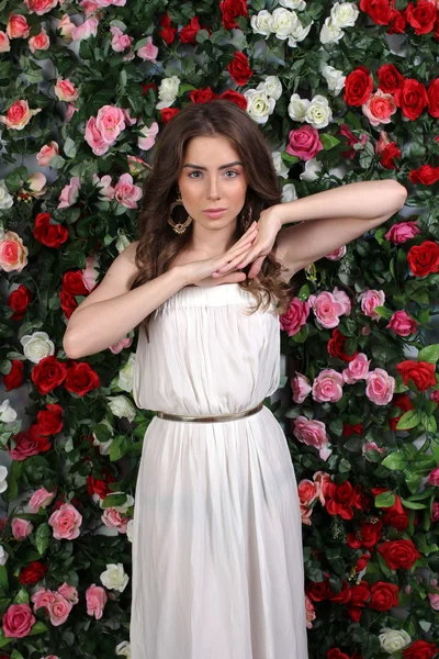 Flicka i vit klänning poserar på floral bakgrund — Stockfoto