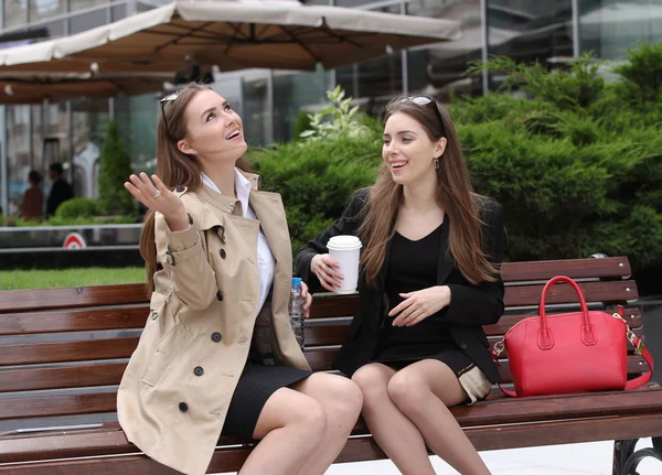Дві дівчини п'ють каву на лавці парку — стокове фото