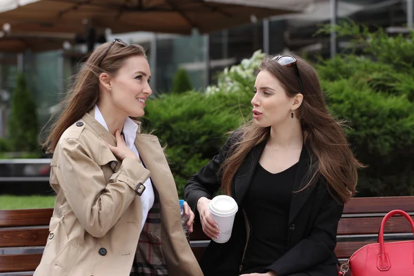 Two girls drinking coffe on a park bench — Stock Photo, Image