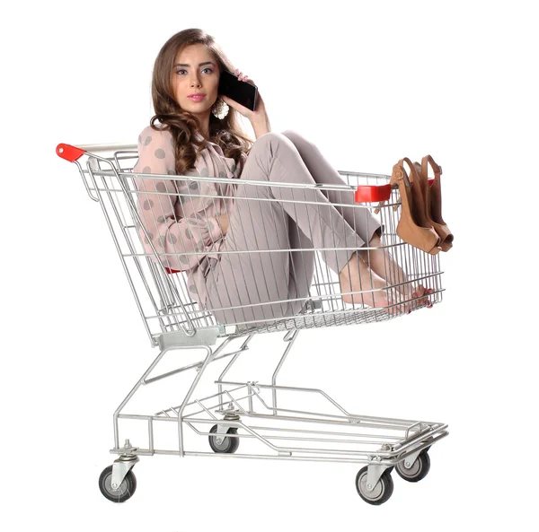 Pretty brunette woman phone speaking in empty shopping trolley — Stock Photo, Image